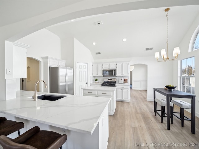 kitchen featuring kitchen peninsula, appliances with stainless steel finishes, light wood-type flooring, sink, and white cabinets