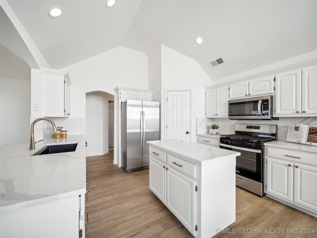 kitchen with stainless steel appliances, white cabinetry, lofted ceiling, and sink