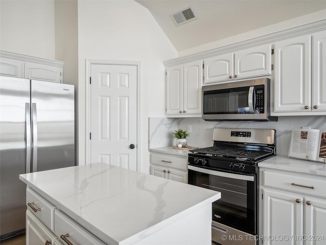 kitchen featuring appliances with stainless steel finishes, tasteful backsplash, white cabinetry, and lofted ceiling