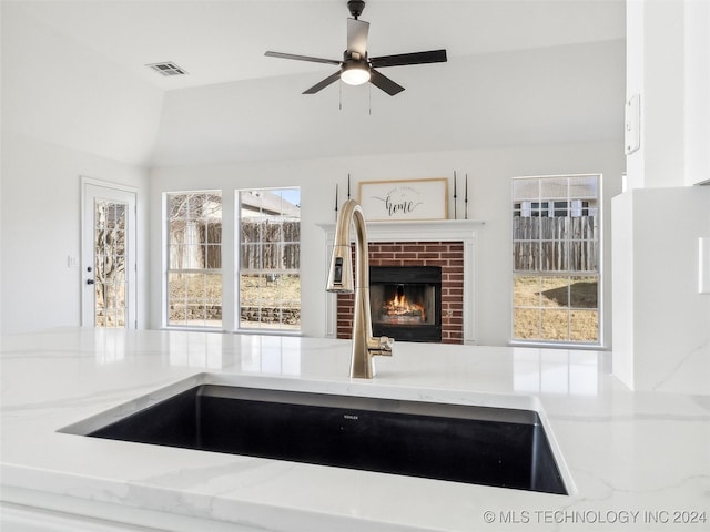 kitchen with a brick fireplace, ceiling fan, a healthy amount of sunlight, and sink