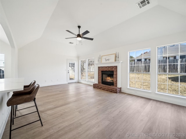 unfurnished living room with ceiling fan, light hardwood / wood-style floors, a fireplace, and high vaulted ceiling