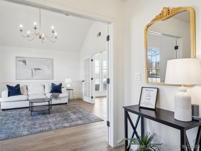 living room with hardwood / wood-style floors, a notable chandelier, and lofted ceiling