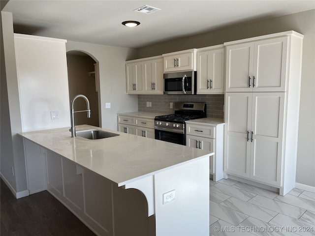 kitchen featuring a kitchen bar, appliances with stainless steel finishes, kitchen peninsula, sink, and white cabinets