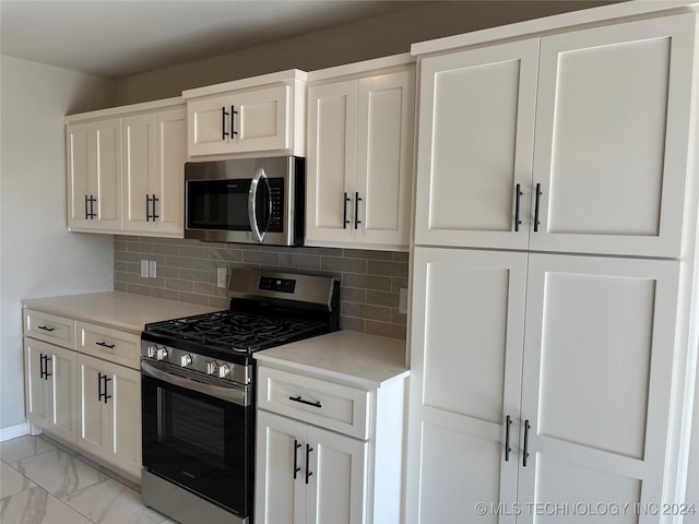 kitchen with white cabinets, backsplash, and appliances with stainless steel finishes