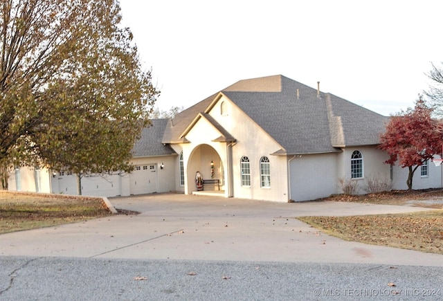 view of front facade featuring brick siding, driveway, a shingled roof, and a garage