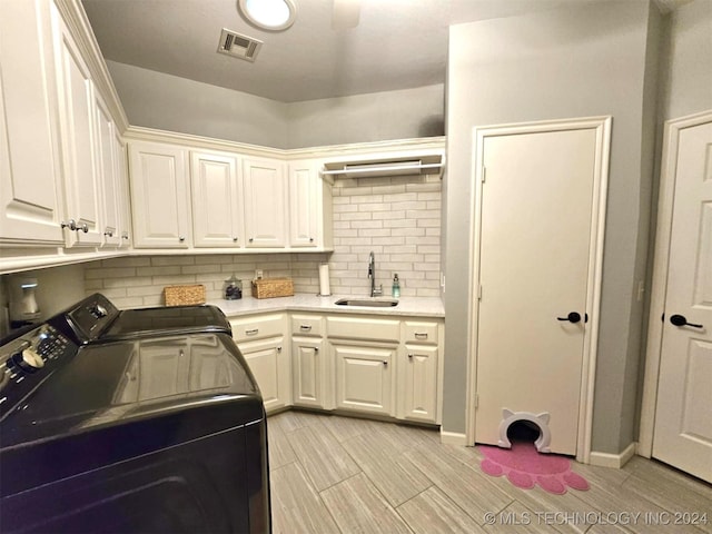 laundry room featuring visible vents, wood tiled floor, washer and dryer, cabinet space, and a sink