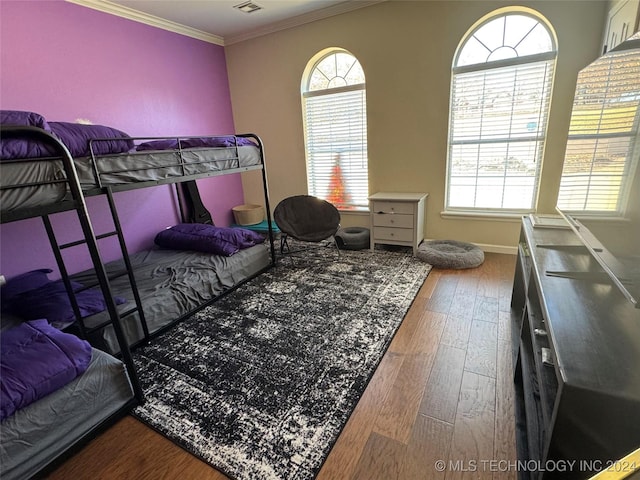 bedroom with visible vents, wood finished floors, and crown molding