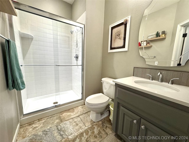 full bathroom featuring a stall shower, toilet, and vanity