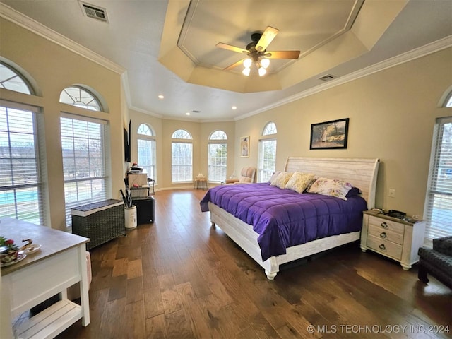 bedroom featuring dark wood finished floors, a raised ceiling, multiple windows, and visible vents