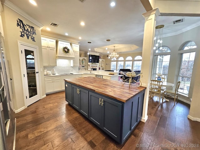 kitchen with a peninsula, black electric stovetop, visible vents, and butcher block countertops