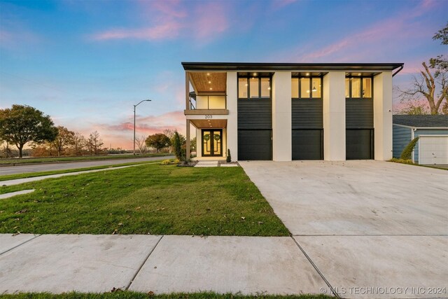 contemporary house featuring french doors, a balcony, and a lawn