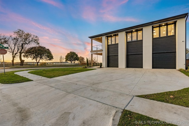 garage at dusk featuring a yard