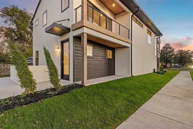 property exterior at dusk featuring a lawn