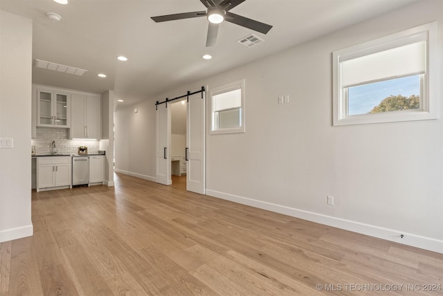 interior space with a barn door, ceiling fan, sink, and light hardwood / wood-style flooring