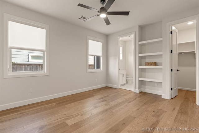 unfurnished bedroom with ensuite bath, ceiling fan, light hardwood / wood-style flooring, a walk in closet, and a closet