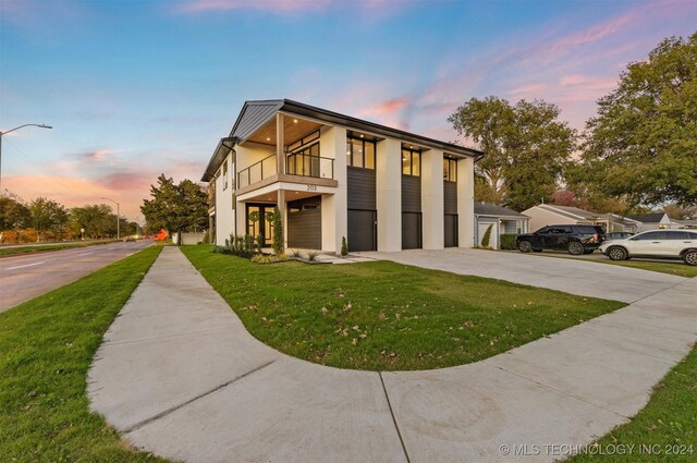 view of front of house featuring a yard and a balcony