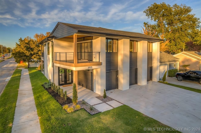 203 E 45th Ct, Tulsa, OK 74105 - back of property with a balcony, stucco siding, concrete driveway, a garage, and a lawn