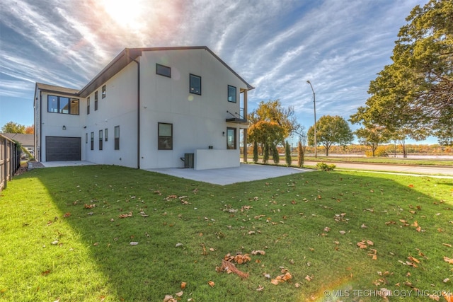 back of house featuring a lawn, a garage, and a patio