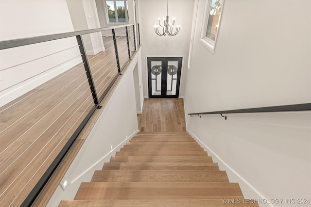 stairway with hardwood / wood-style floors and an inviting chandelier