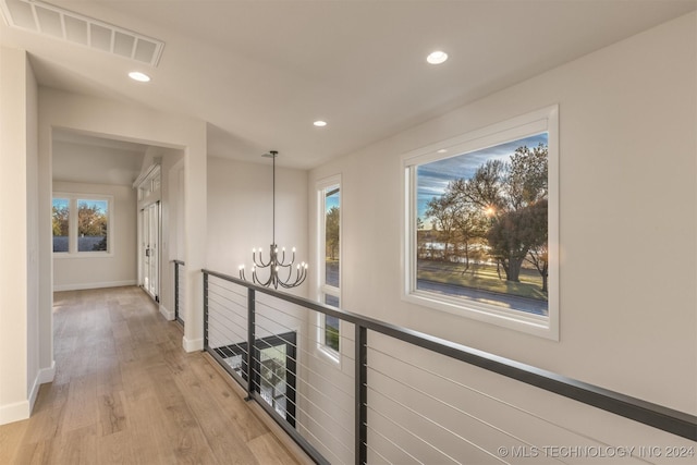 hall featuring light wood-type flooring and an inviting chandelier