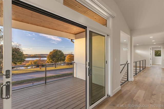 entryway with hardwood / wood-style floors, a water view, and lofted ceiling