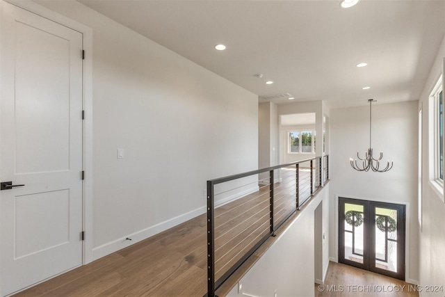 hallway featuring light hardwood / wood-style floors, french doors, and a chandelier