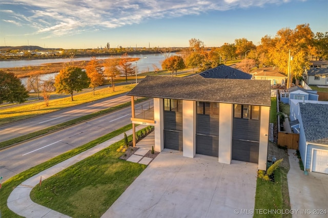 view of front facade with a garage, a water view, and a balcony