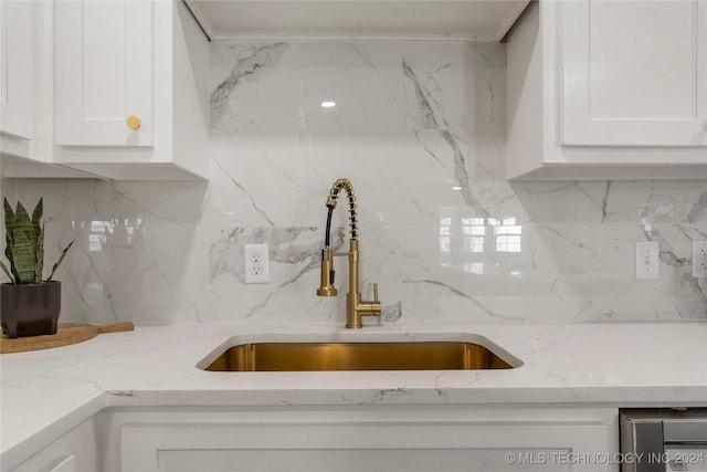 kitchen with backsplash, light stone counters, sink, and white cabinets