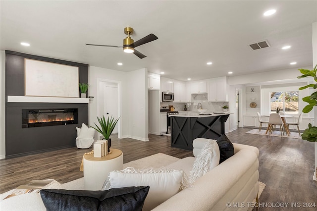 living room with dark hardwood / wood-style flooring and ceiling fan