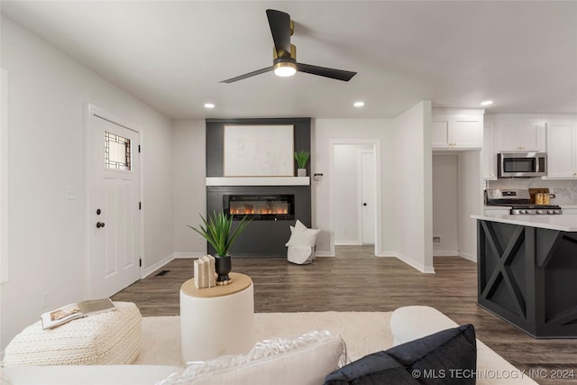 living room with dark hardwood / wood-style floors, ceiling fan, and a fireplace