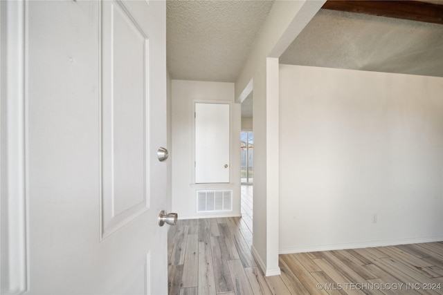 corridor with a textured ceiling and light wood-type flooring