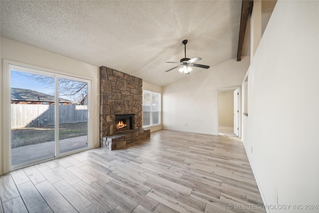 unfurnished living room featuring ceiling fan, light wood-type flooring, a textured ceiling, a fireplace, and beam ceiling