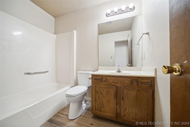 full bathroom with bathing tub / shower combination, hardwood / wood-style floors, a textured ceiling, toilet, and vanity