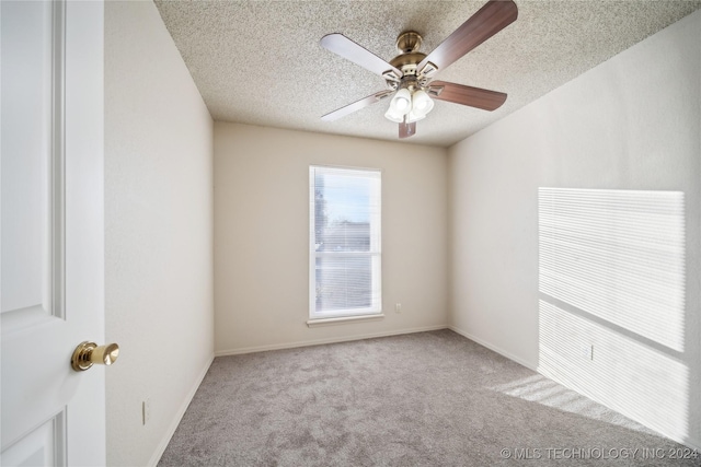 empty room featuring light carpet, ceiling fan, and a textured ceiling