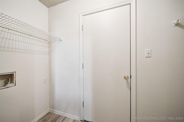 clothes washing area with washer hookup, a textured ceiling, and light hardwood / wood-style flooring