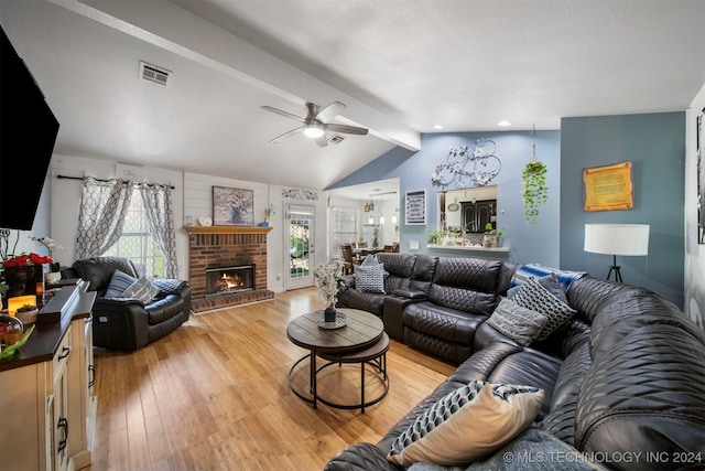 living room featuring a brick fireplace, lofted ceiling with beams, light hardwood / wood-style flooring, and ceiling fan