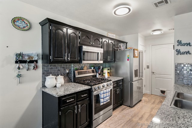 kitchen featuring light stone countertops, sink, appliances with stainless steel finishes, and tasteful backsplash