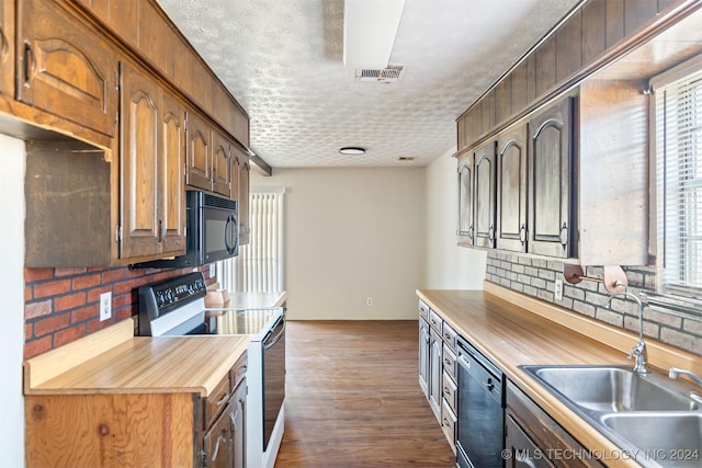 kitchen with butcher block counters, sink, dark hardwood / wood-style flooring, a textured ceiling, and black appliances