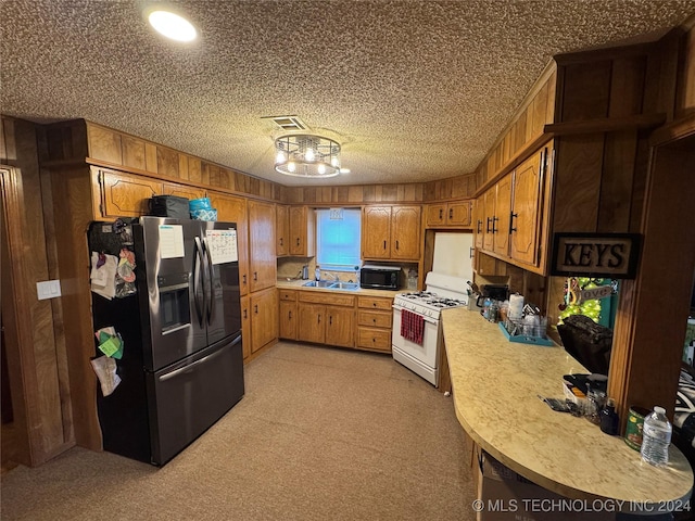 kitchen featuring light carpet, sink, stainless steel refrigerator with ice dispenser, a textured ceiling, and white range with gas cooktop