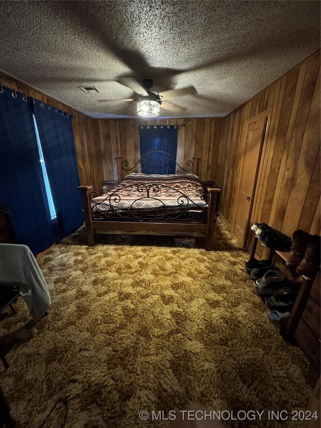 carpeted bedroom featuring a textured ceiling, ceiling fan, and wooden walls