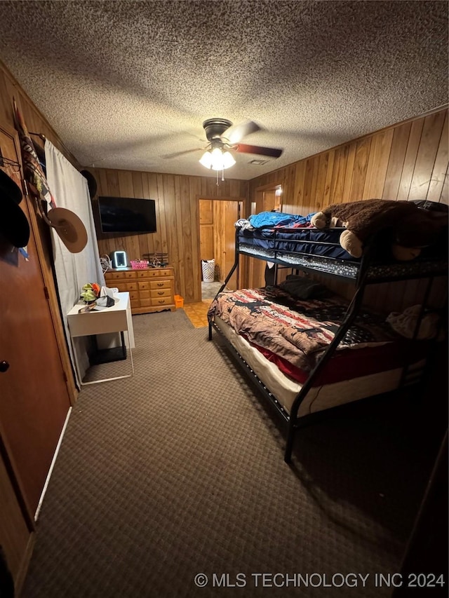 bedroom with carpet, ceiling fan, a textured ceiling, and wooden walls