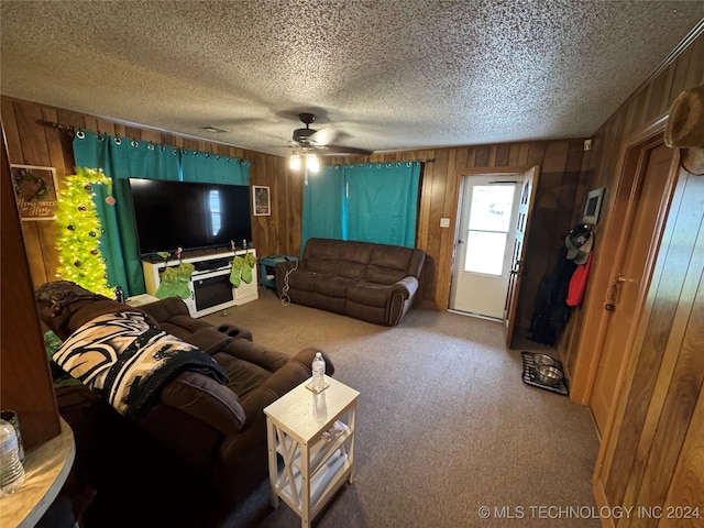 living room featuring carpet flooring, a textured ceiling, ceiling fan, and wooden walls