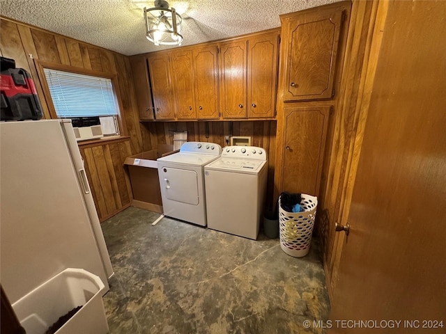 washroom featuring washing machine and dryer, wood walls, cabinets, and a textured ceiling