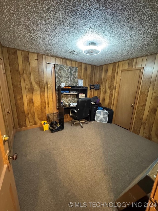 unfurnished office with a textured ceiling, carpet floors, and wood walls