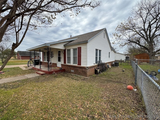 view of front of property with a front lawn, covered porch, and central AC