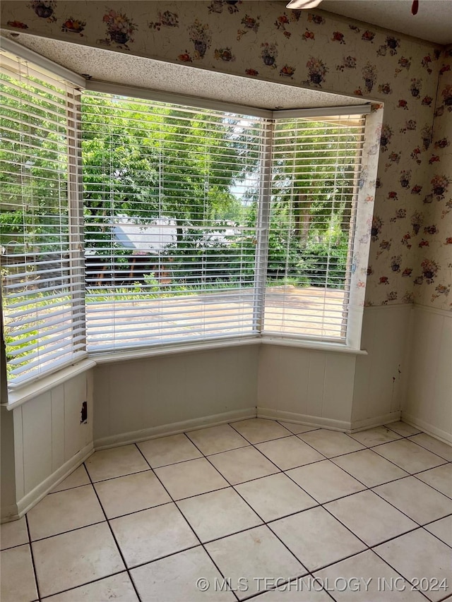 spare room with a wealth of natural light and light tile patterned flooring