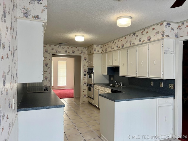 kitchen with white cabinetry, sink, double oven, a textured ceiling, and light tile patterned flooring