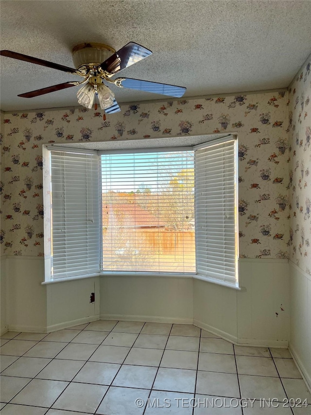 tiled empty room featuring ceiling fan and a textured ceiling