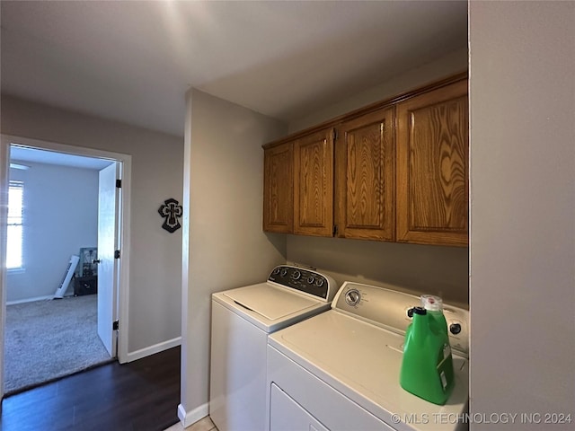 washroom with washer and dryer, cabinets, and dark wood-type flooring