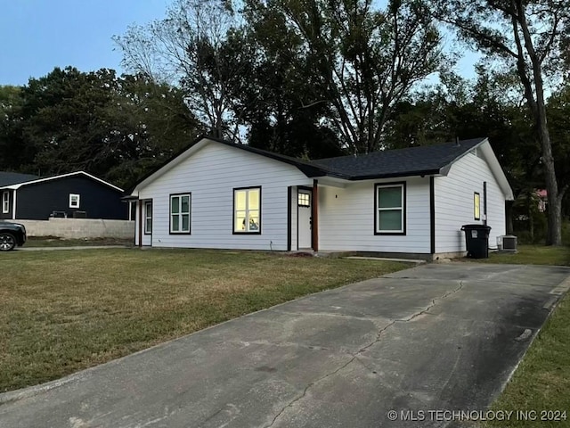 ranch-style house featuring central air condition unit and a front lawn